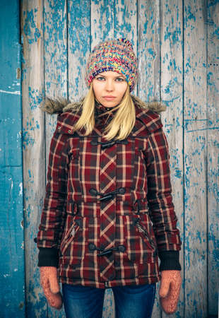 Sad Woman wearing knitted hat and mittens trendy scandinavian Lifestyle melancholy and solitude concept winter time with old wooden backgroundの写真素材