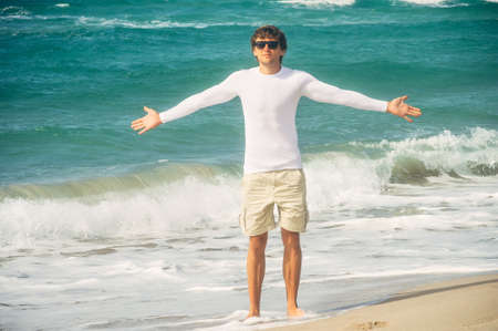 Man Traveler with raised hands outdoor Sea on background Freedom Lifestyle conceptの写真素材