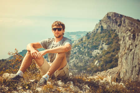 Young Man relaxing outdoor with mountains on background Summer vacations and Lifestyle hiking conceptの写真素材