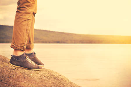 Feet man walking outdoor Travel Lifestyle vacations concept with lake and sun on background retro colorsの写真素材
