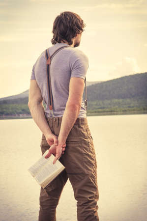 Young Man Traveler with book outdoor Travel Lifestyle concept mountains on backgroundの写真素材