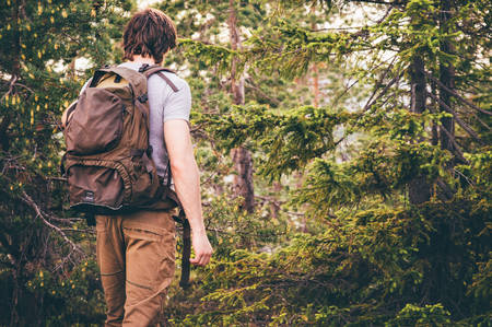 Young Man hiking in forest with backpack Travel Lifestyle and outdoor recreation summer vacations conceptの写真素材