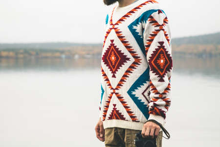 Man with retro photo camera Fashion Travel Lifestyle wearing knitted sweater clothing outdoor foggy nature on backgroundの写真素材
