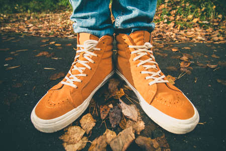 Feet sneakers walking on fall leaves Outdoor with Autumn season nature on background Lifestyle Fashion trendy styleの写真素材