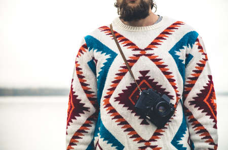 Young Man bearded with retro photo camera Fashion Travel Lifestyle wearing knitted sweater clothing outdoor foggy nature on backgroundの写真素材