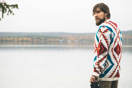 Young Man bearded with retro photo camera Fashion Travel Lifestyle wearing knitted sweater clothing outdoor foggy nature on backgroundの写真素材