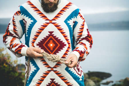 Man hands holding rope knot Travel Lifestyle survival concept wearing knitted sweater outdoor foggy nature on backgroundの写真素材