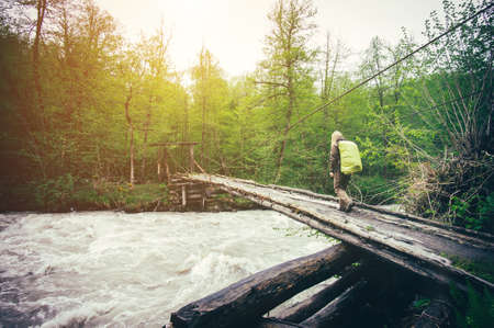 Woman Traveler with backpack hiking on bridge over river Travel Lifestyle concept forest on background Summer journey vacations outdoorの写真素材
