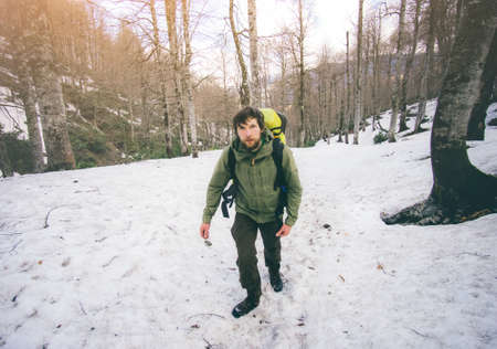 Man Traveler with backpack hiking in snow forest mountains Travel Lifestyle concept outdoorの写真素材