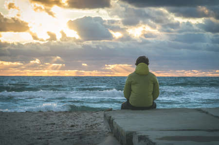Man Traveler relaxing alone on beach seaside with sea waves and sunset sky on background summer vacations Travel Lifestyle conceptの写真素材