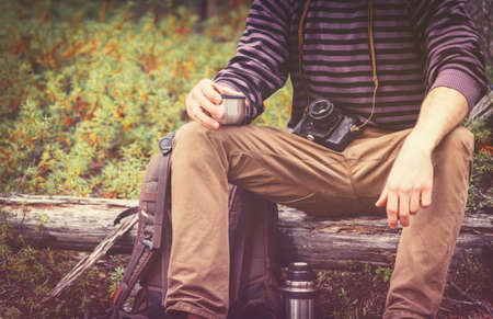Traveler Man relaxing in forest with photo camera, backpack and  drinking tea Travel Lifestyle concept Summer vacations outdoorの写真素材
