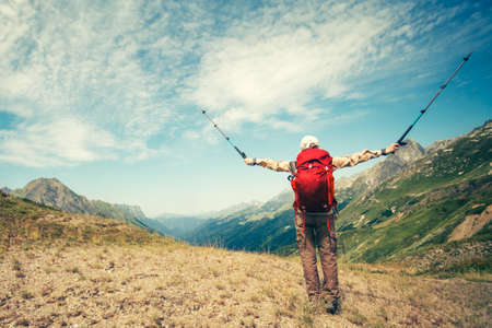 Happy Woman Traveler with backpack hands raised trekking poles enjoying mountains landscape Travel Lifestyle concept adventure vacationsの写真素材