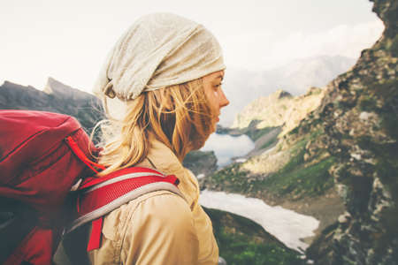 Young Woman with red backpack hiking alone Travel Lifestyle concept lake and mountains landscape on background Summer vacations outdoor. windy soft focusの写真素材