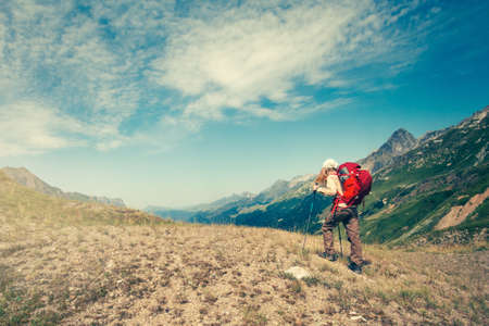 Woman with backpack mountaineering Travel Lifestyle concept active vacations outdoor mountains and clouds on backgroundの写真素材
