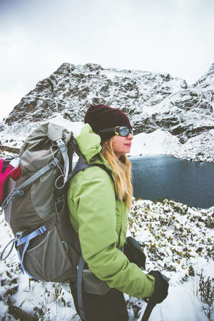 Woman backpacker hiking Travel Lifestyle adventure concept snow rocky mountains and lake on background winter vacationsの写真素材