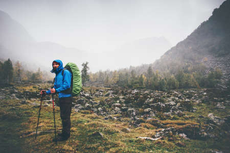Traveler Man with backpack hiking Travel Lifestyle concept rainy cloudy mountains and forest landscape on background adventure vacations outdoorの写真素材