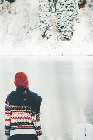 Woman alone in winter forest and lake Travel Lifestyle adventure concept vacations into the wildの写真素材