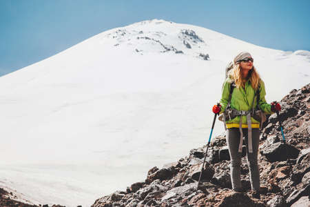 Woman traveler with backpack hiking in mountains Travel Lifestyle adventure concept active vacations outdoor mountaineering sport success Elbrus mountain on backgroundの写真素材