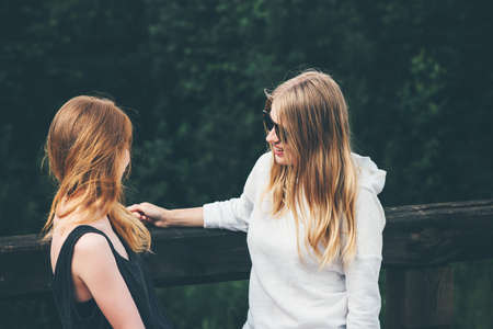 Couple girls talking together enjoying summer vacations blonde young women fashion lifestyle emotions conceptの写真素材