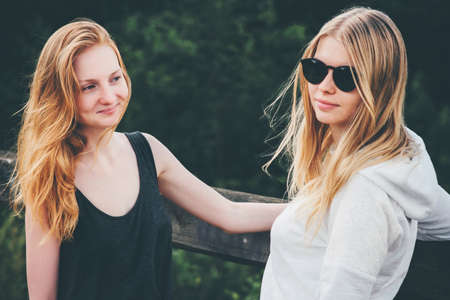 Couple girls walking together enjoying summer vacations blonde young women fashion lifestyle emotions conceptの写真素材