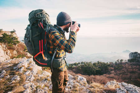 Man traveler photographer with backpack and camera taking photo of mountains Travel Lifestyle hobby concept adventure summer vacations outdoor の写真素材