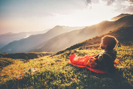Man relaxing in sleeping bag enjoying sunset mountains landscape Travel Lifestyle camping concept adventure summer vacations outdoor hiking mountaineering harmony with natureの写真素材