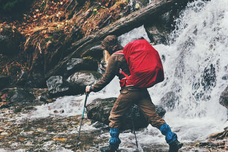 Woman traveler with red backpack hiking at waterfall Lifestyle adventure vacations concept outdoor waterfall on background rainy moody weatherの写真素材
