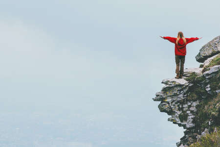 Happy traveler standing on cliff mountain hands raised Travel Lifestyle success motivation concept adventure active vacations outdoor foggy clouds on backgroundの写真素材