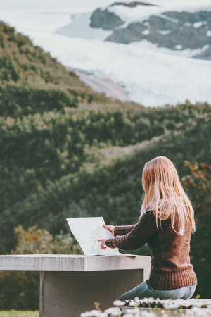 Woman with map planning journey route in Norway sitting at the table Travel Lifestyle concept adventure vacations outdoorの写真素材