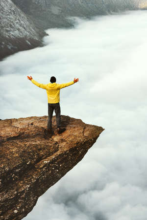 Man tourist success raised hands on Trolltunga rocky cliff edge in Norway mountains Travel Lifestyle adventure concept vacations outdoor above clouds の写真素材