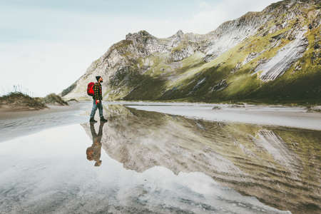 Man walking alone at sandy beach in mountains Travel lifestyle emotional concept adventure outdoor summer vacations wild nature water reflectionの写真素材