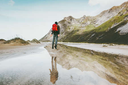 Traveler Man jumping in mountains Travel lifestyle emotional spiritual concept adventure outdoor water reflectionの写真素材