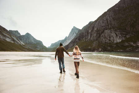Romantic Couple in love walking holding hands on sea beach in Norway man and woman together traveling Lifestyle concept vacations outdoorの写真素材