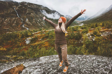 Happy woman traveler raised hands walking in forest mountainsの写真素材
