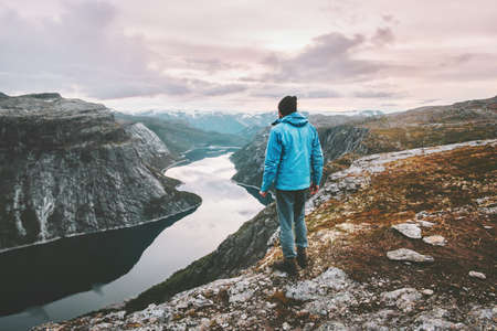 Hiker man traveling alone walking in sunset mountains landscape adventure journey lifestyle vacations weekend getaway aerial Norway lake landscape  の写真素材