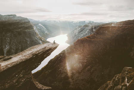 Man sitting alone on Trolltunga cliff edge in Norway travel adventure lifestyle active vacations getaway outdoor sunset mountains over lake landscape
の写真素材