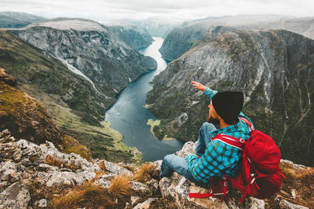 Man backpacker relaxing on mountain cliff traveling in Norway active lifestyle weekend getaway adventure vacations aerial view Naeroyfjord landscapeの写真素材