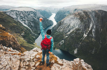 Brave Man traveling in Norway mountains standing on cliff active lifestyle weekend getaway adventure vacations success  concept aerial view fjord landscapeの写真素材