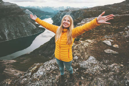 Happy girl success raised hands standing on mountain summit hiking travel adventure lifestyle vacations weekend getaway aerial  lake landscape in Norway の写真素材