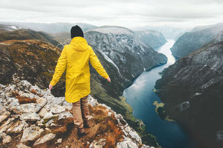 Traveler walking alone in mountains weekend getaway adventure lifestyle scandinavian vacations aerial Norway fjord landscape  の写真素材