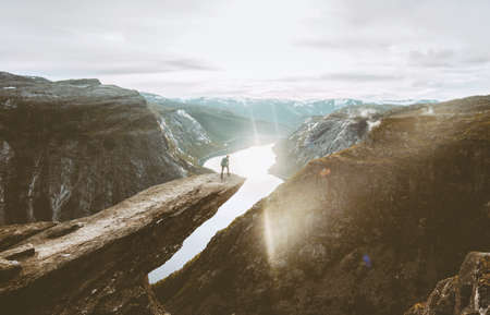 Trolltunga cliff and man traveler standing on edge in Norway adventure travel extreme lifestyle active vacations outdoor sunset mountains and lake 
の写真素材
