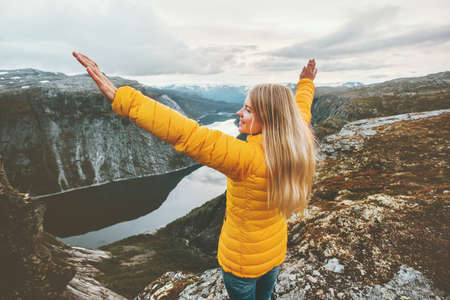 Young woman happy raised hands on mountain top travel adventure lifestyle journey vacations aerial lake landscape success wellness emotions の写真素材