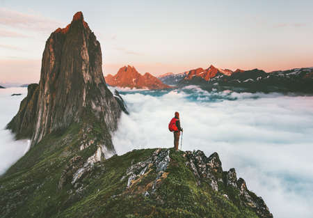 Traveler on cliff over clouds exploring sunset Segla mountain alone hiking adventure journey outdoor Norway vacations traveling lifestyle weekend getawayの写真素材