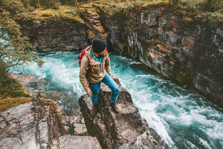 Adventurer man hiking alone active lifestyle extreme vacations outdoor on cliff above river canyon in Swedenの写真素材