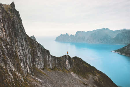 Travel Norway vacations man standing alone on cliff above fjord adventure lifestyle solitude silence concept scandinavian climbing outdoor の写真素材