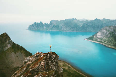 Norway vacations woman standing alone on cliff mountain edge above sea travel adventure lifestyle outdoor Senja islands landscapeの写真素材