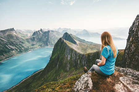 Woman enjoying mountain view traveling healthy lifestyle adventure summer vacations girl relaxing alone on cliff over fjord outdoor in Norwayの写真素材