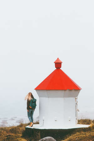 Woman tourist walking near lighthouse Travel lifestyle adventure trip outdoor in Norway foggy seaside on backgroundの写真素材