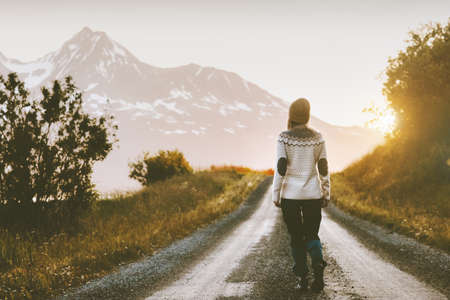 Woman walking alone on gravel road in mountains Travel lifestyle adventure vacations escape outdoorの写真素材