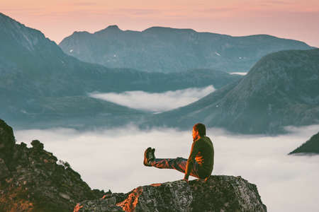 Man training sports on mountain cliff above clouds alone travel healthy lifestyle adventure journey outdoor vacations の写真素材